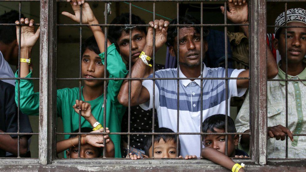 Rohingya men and children looking out from a window in temporary shelter in Lhokseumawe, Aceh