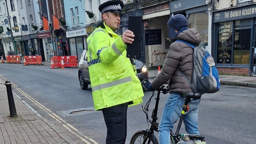 A policeman stopping a cyclist in the road