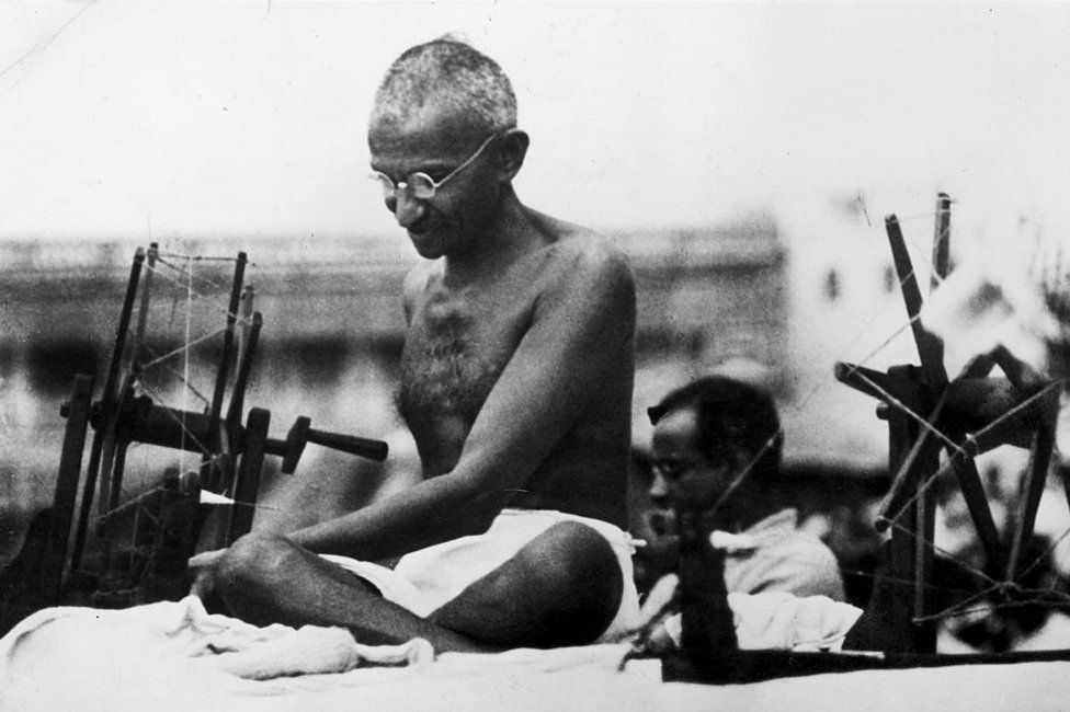 9th June 1925: Indian Nationalist leader Mahatma Gandhi (Mohandas Karamchand Gandhi, 1869 - 1948) at a spinning wheel during a 'Charlea' demonstration in Mirzapur, Uttar Pradesh.