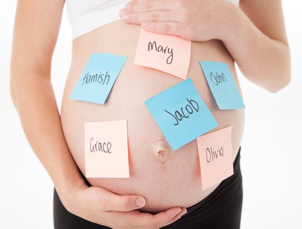 A pregnant tummy with post it notes with baby names stuck all over it