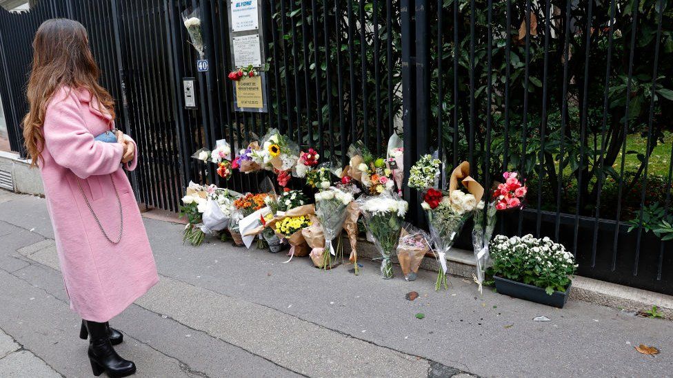 A woman looks at flowers displayed outside the building where a 12-year-old schoolgirl Lola lived and who was murdered on October 18, 2022 in Paris, France