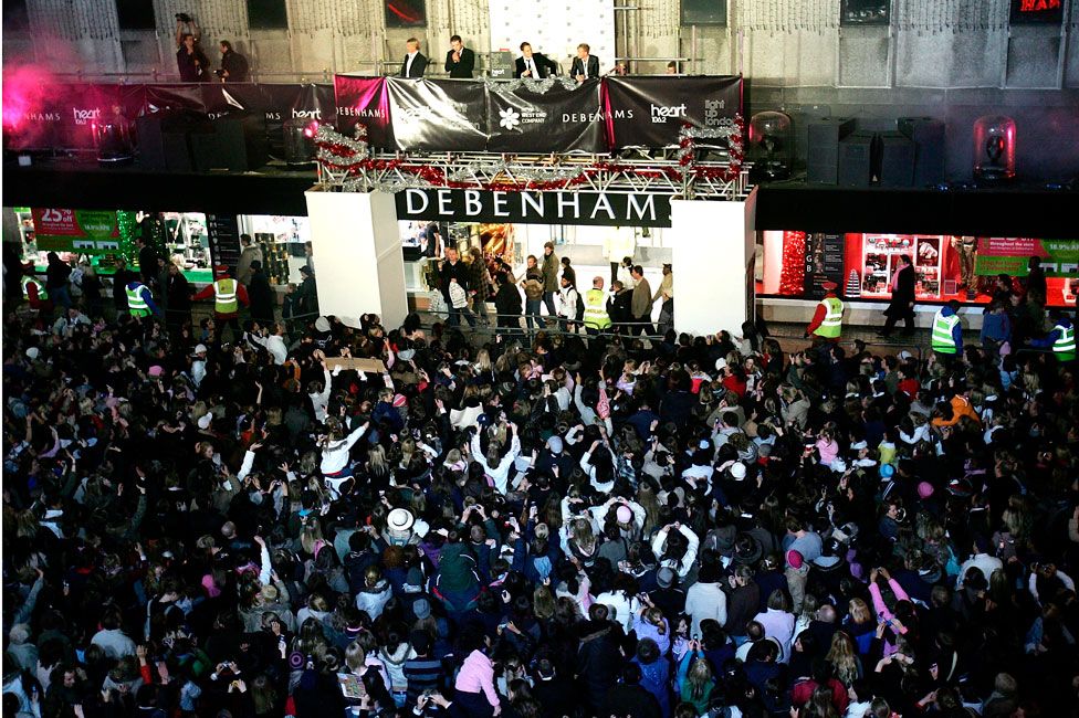 Westlife perform to a crowd outside of a Debenhams store