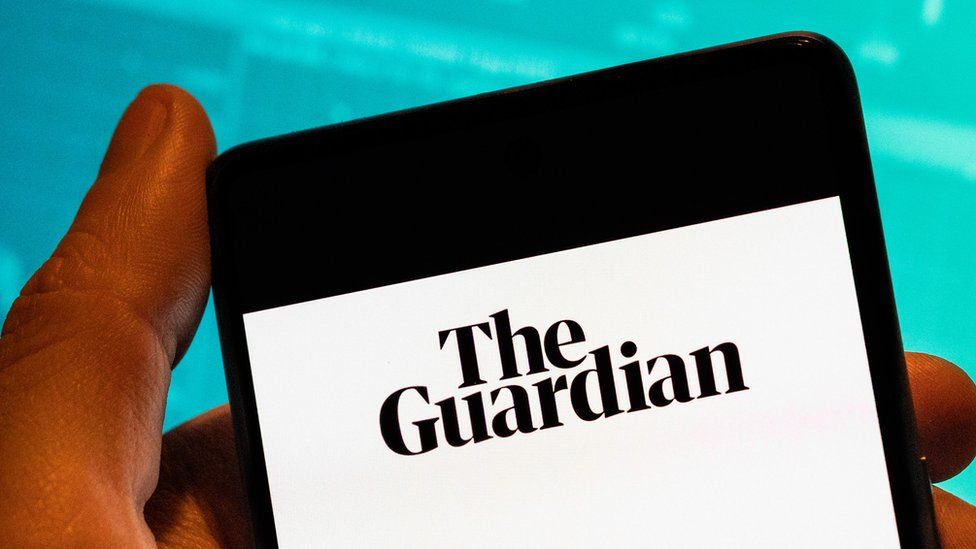 Человек держит телефон с приложением газеты The Guardian
