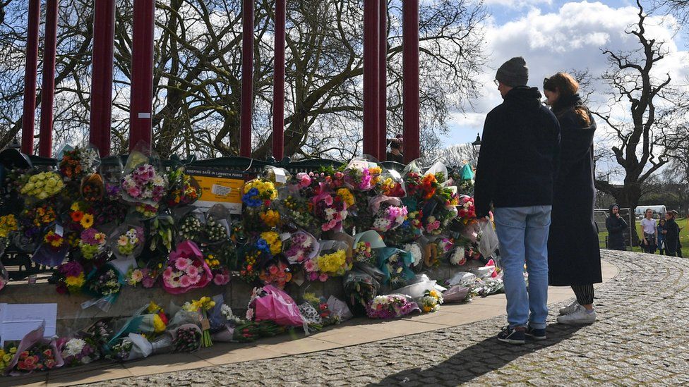 A man and a woman gather at a site where flowers have been laid in memory of Sarah Everard