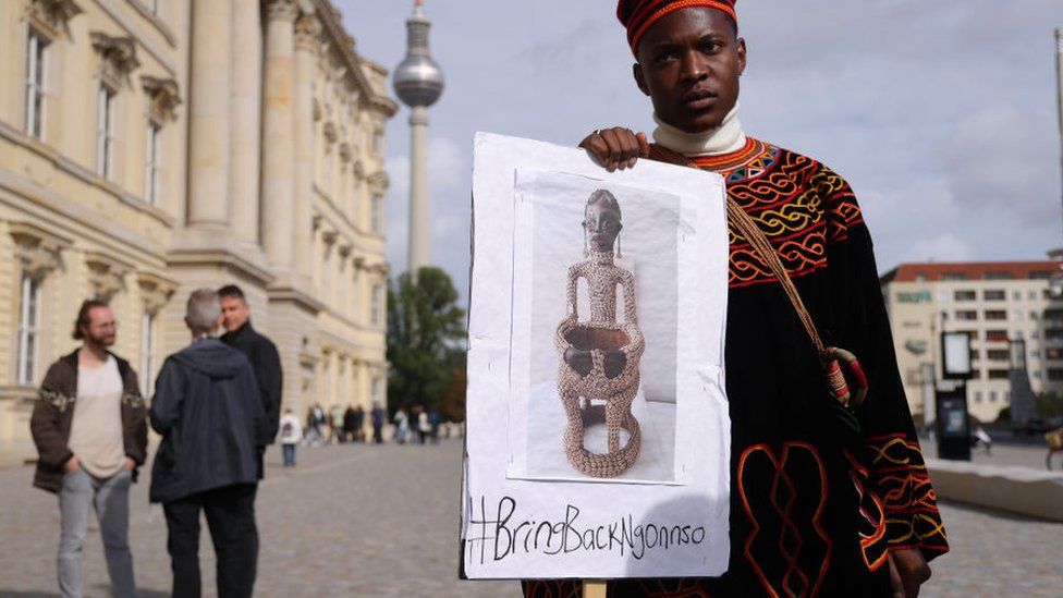 A protester from Cameroon seeking the return of the Ngonnso statue stands outside the Humboldt Forum