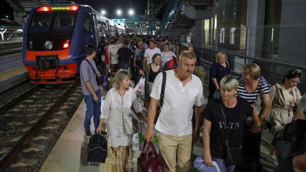 Passengers walk out of a train, which arrived on the Crimean bridge connecting the Russian mainland with the peninsula across the Kerch Strait, to the railway station in the town of Kerch, Crimea, July 17, 2023.