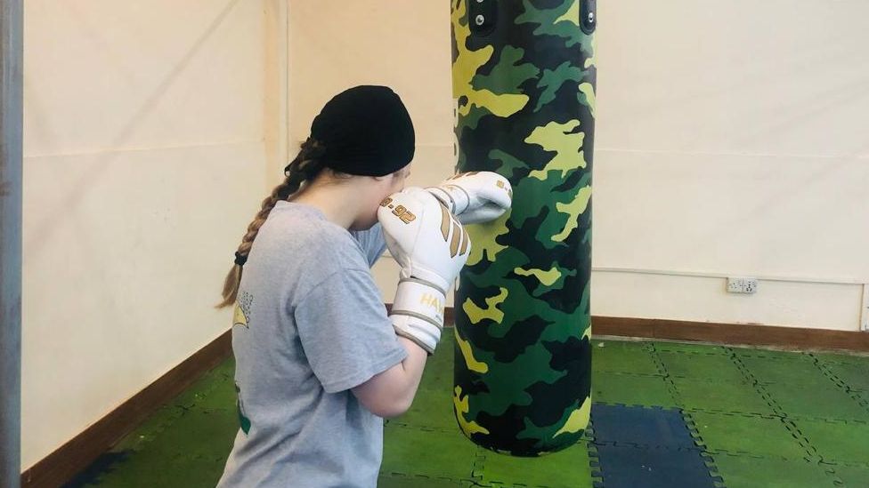 Nina with boxing gloves punching a bag