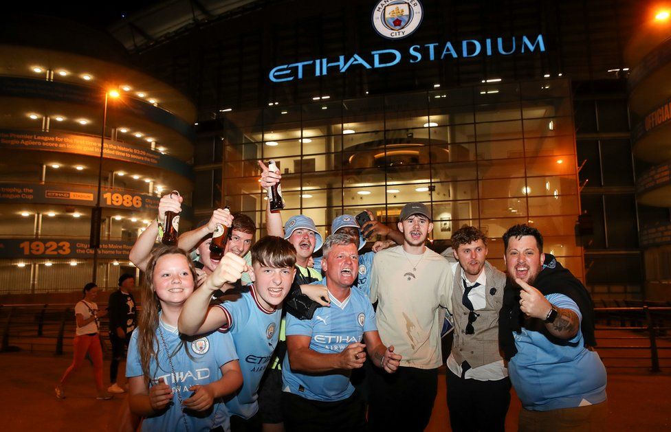 Manchester City fans outside the Etihad Stadium celebrate their side's victory