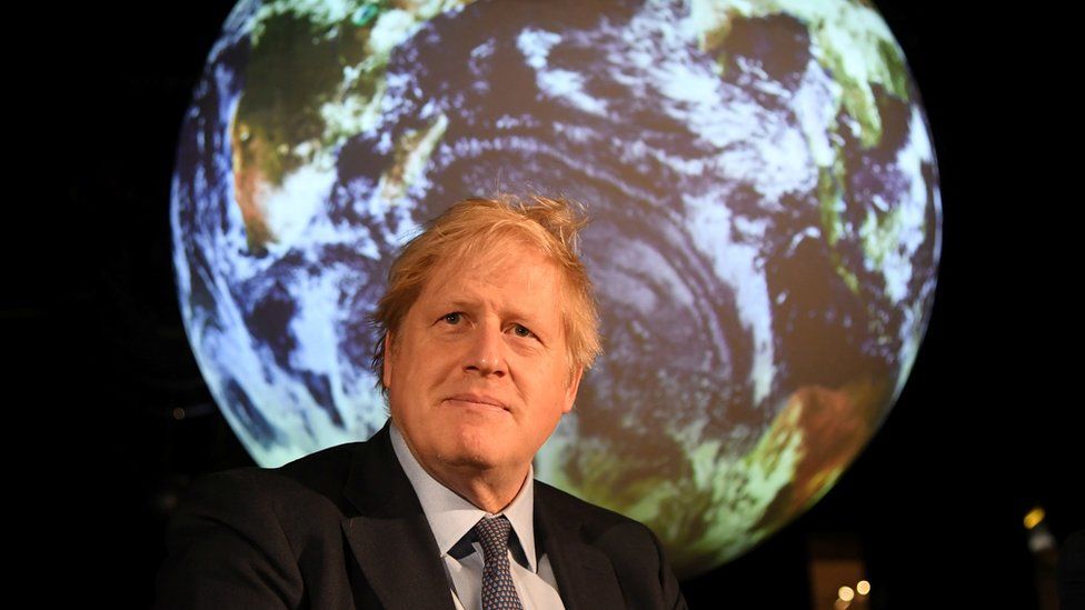 Boris Johnson sitting in front of an image of planet earth at the COP26 UN Climate Summit.