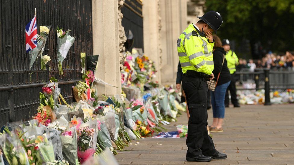 A police officer reacts as he stands guard in front of Buckingham Palace