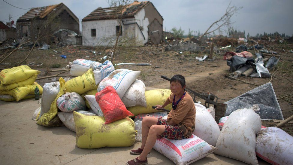 A woman sits with her belongings in front of the rubble of her destroyed houses after a tornado in Funing, in Yancheng, in China"s Jiangsu province on June 24, 2016.