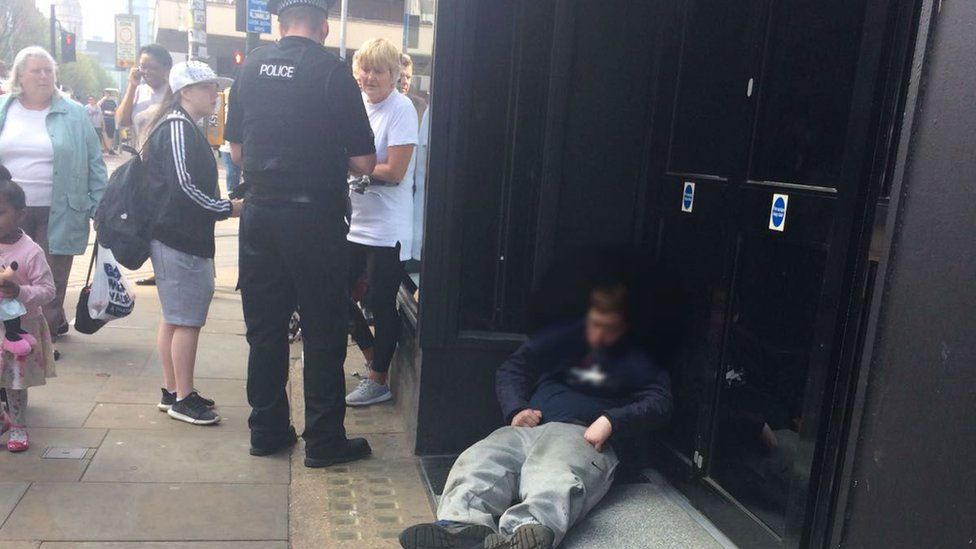 Man slumped in doorway in Manchester with policeman nearby