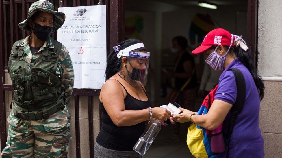 Woman having hand sanitiser applied at an election registration station in Venezuela