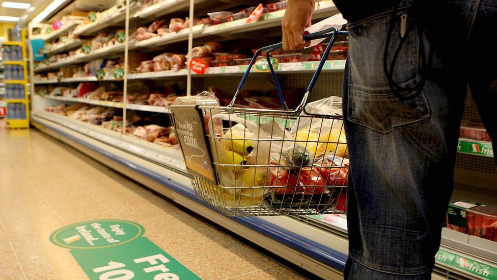 Man carrying shopping basket in supermarket