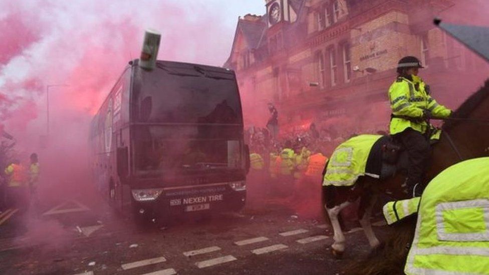 Manchester City bus driving past crowds and flares