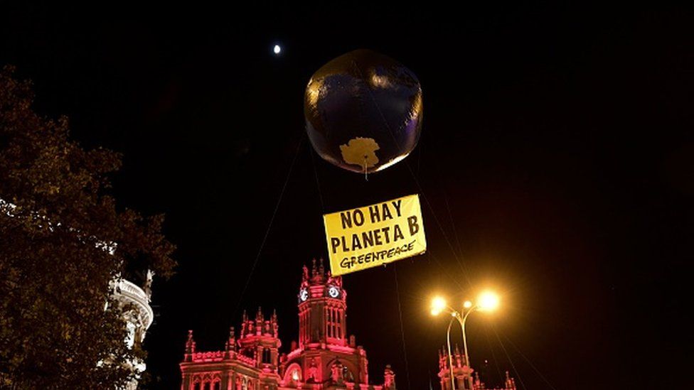 A balloon in the shape of the Earth is pictured with a placard reading "there is no Planet B"