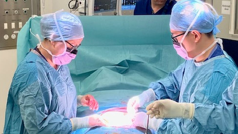 Surgeon Shelly Griffiths closes an ileostomy on a patient under a surgical gown