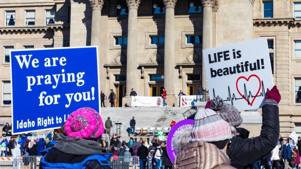 Demonstrators walk to the Idaho Capitol building carrying anti-abortion signs in January 2023