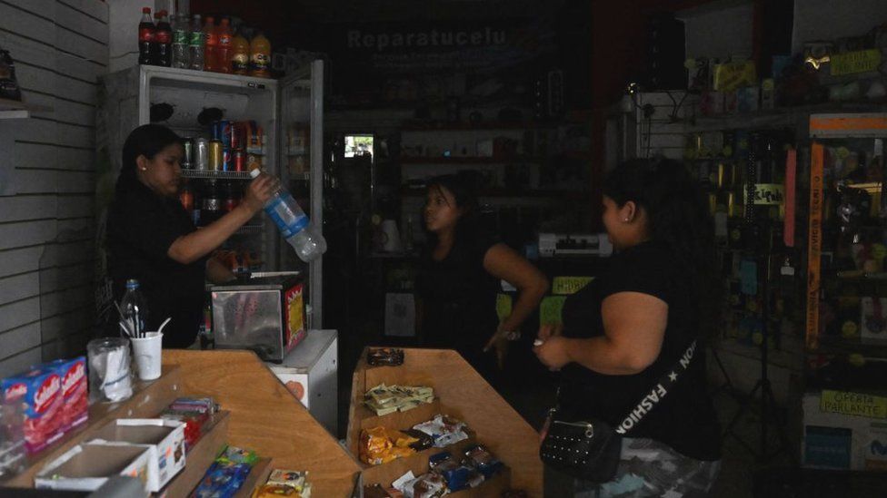 A woman buys water at a shop in the dark in Buenos Aires