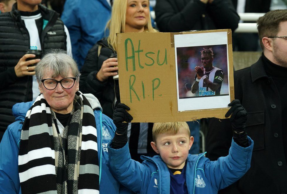 A Newcastle United fan holds up a sign in memory of Christian Atsu on 18 February. Atsu has died following the devastating earthquake that hit Turkey.