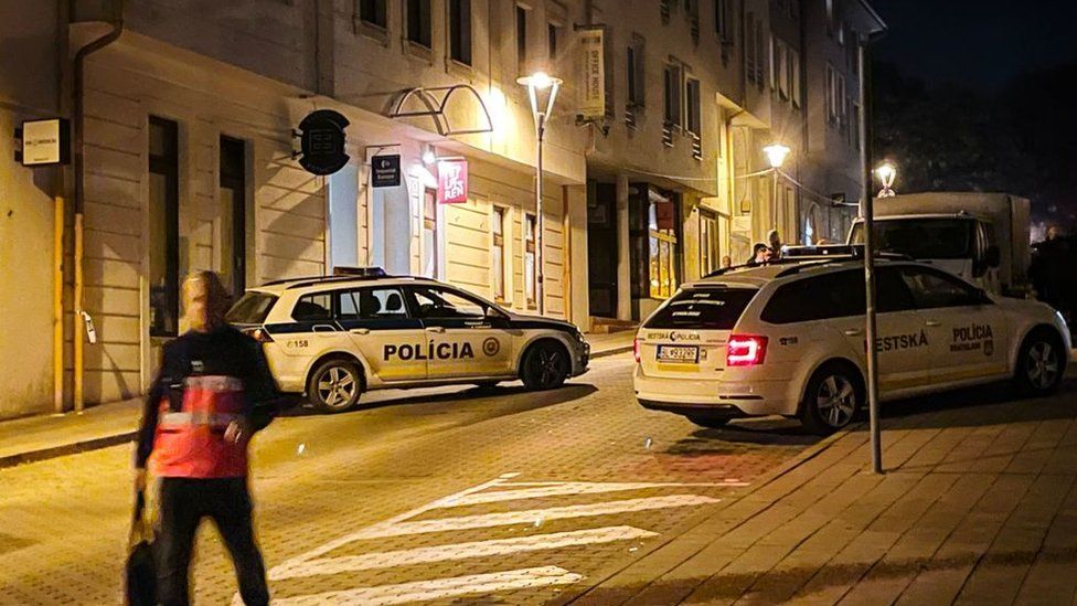 Police cars and officers attend the scene on a Bratislava street following a shooting outside an LGBT bar
