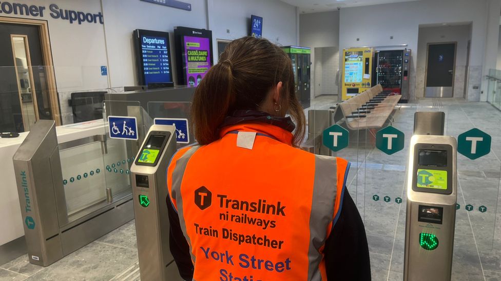 Translink staff member with her back to camera standing inside the station