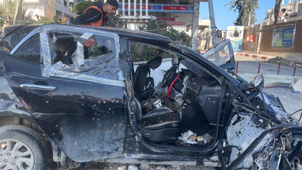 Destroyed car riddled with bullet holes