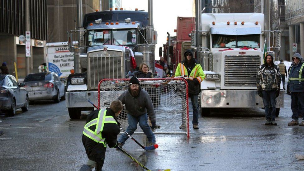 Протестующие играют в уличный хоккей, когда грузовики блокируют улицу в центре Оттавы