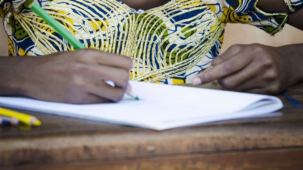 An girl at a desk in Africa drawing - stock image