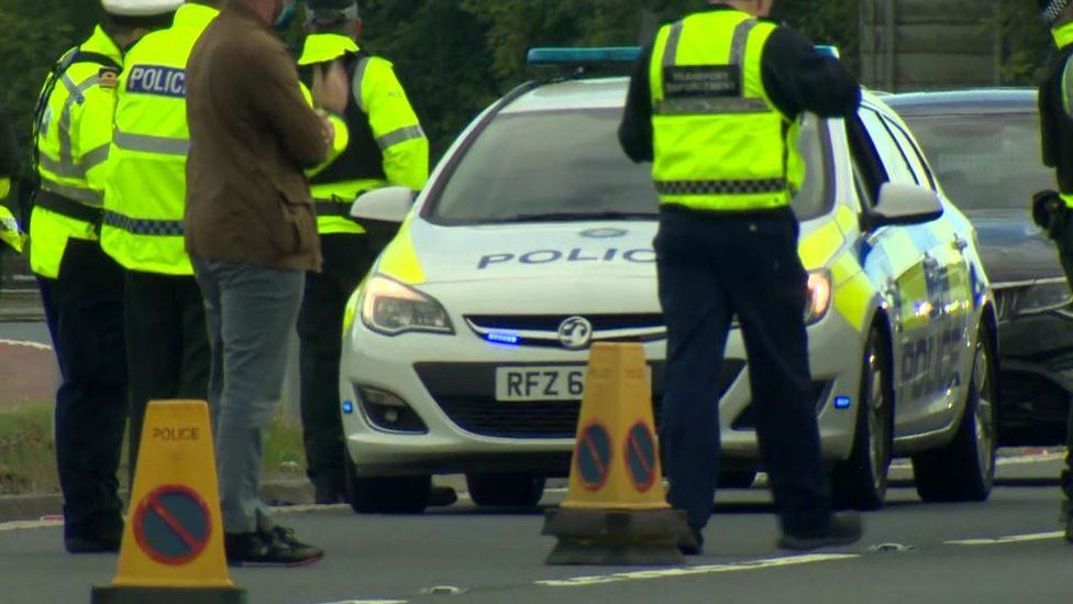 Members of the PSNI taking part in the operation dressed in high-vis jackets and standing near to a police car