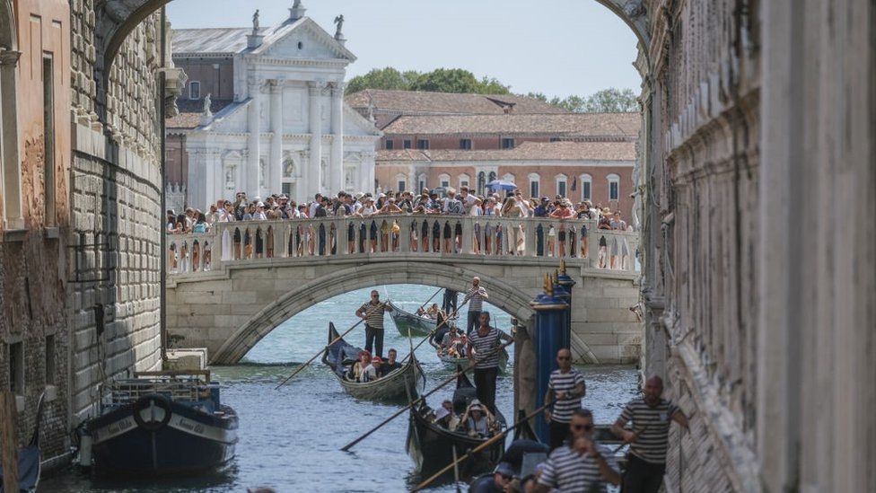 Gondolas slowly pass under the Bridge of Sighs near St. Mark's Square due to too much traffic in Venice, August 2023