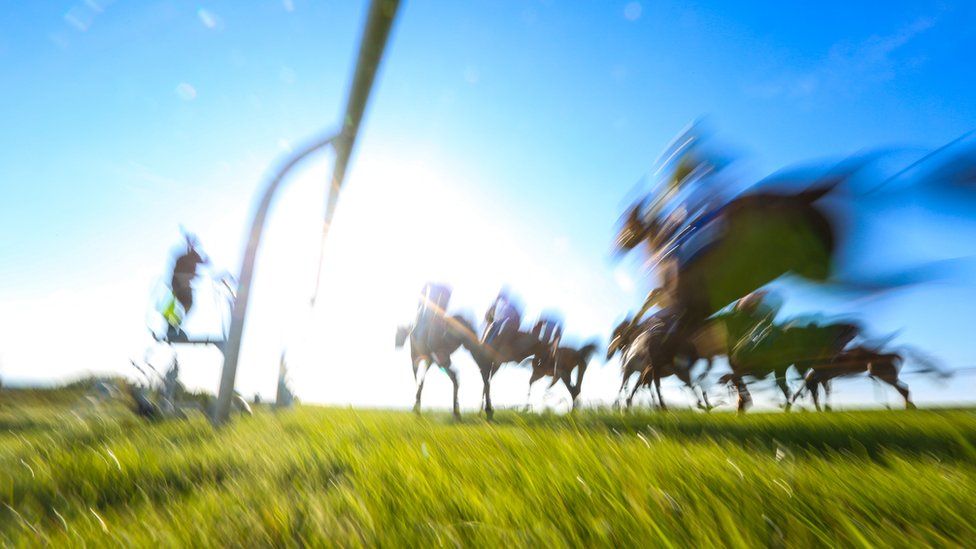 Low angle view of horses running in a race. The image is also blurred.