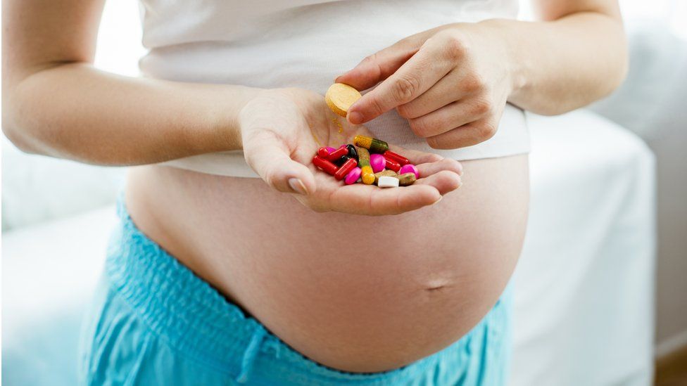 Pregnant lady holding vitamins