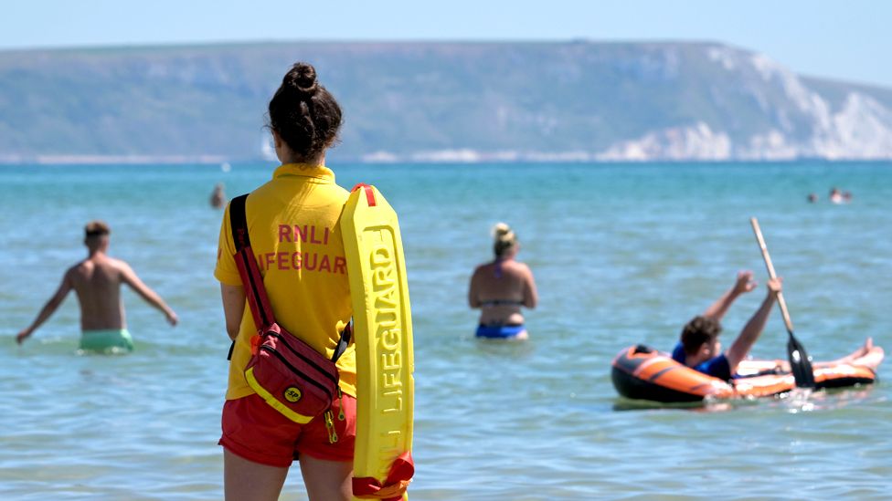 A RNLI lifeguard patrols a beach in Weymouth, England