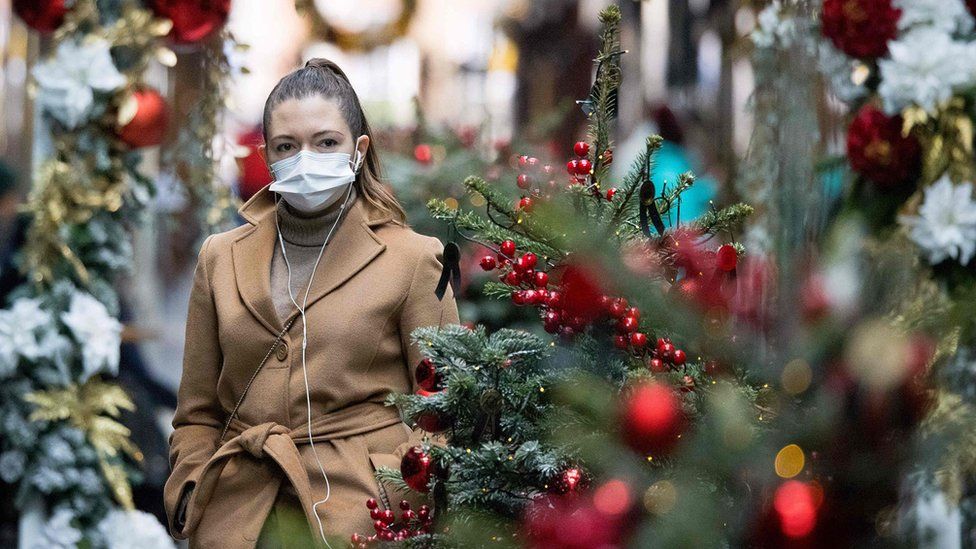 Woman in face mask by Christmas decorations