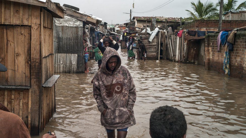 Мадагаскарцы гуляют среди наводнения от тропического циклона в районе Анкорондрано Андраномахери в столице Антананариву, Мадагаскар, 23 января 2022 года.