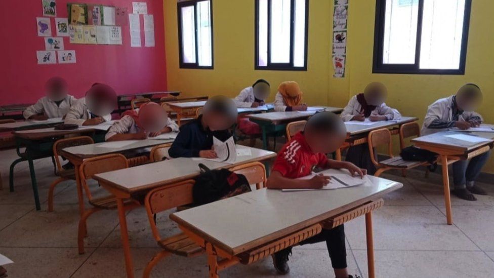 Fëmijë të ulur në një klasë duke bërë detyrat e shkollës
