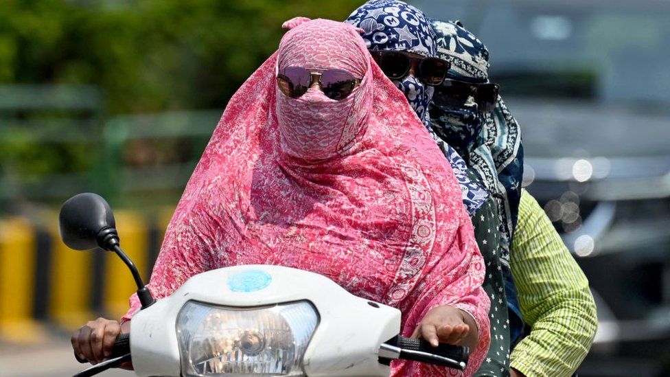 Women cover their faces with a cloth while riding a two-wheeler on a hot day, in Raipur on April 15, 2024. (Photo by Idrees MOHAMMED / AFP) (Photo by IDREES MOHAMMED/AFP via Getty Images)