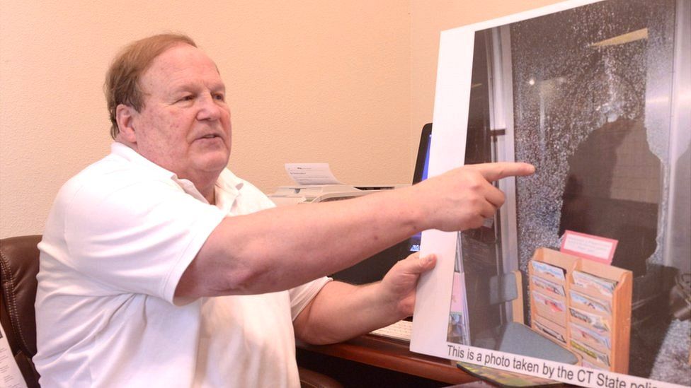 Wolfgang Halbig points to a photo of the Sandy Hook crime scene