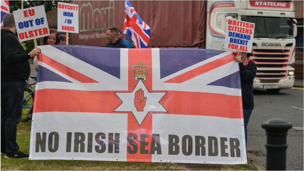 Loyalists protest Northern Ireland Protocol with a sign reading 