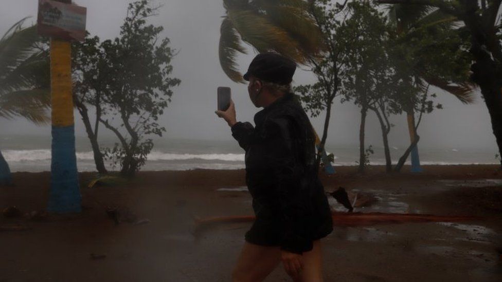 A woman records with her cell phone the strong waves due to the Laura storm in Guayama, southern Puerto Rico, 22 August 2020.