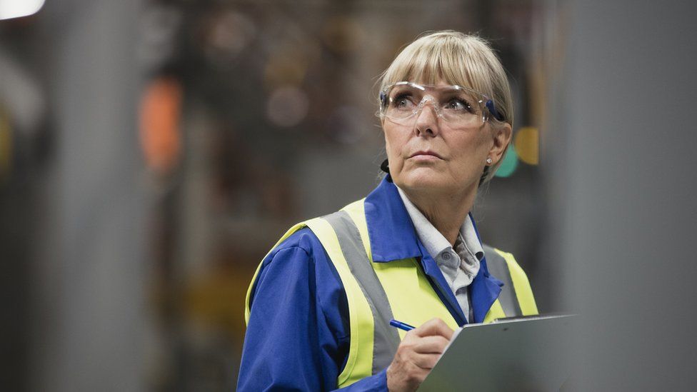 Over-50s woman wearing high vis and goggles in a factory