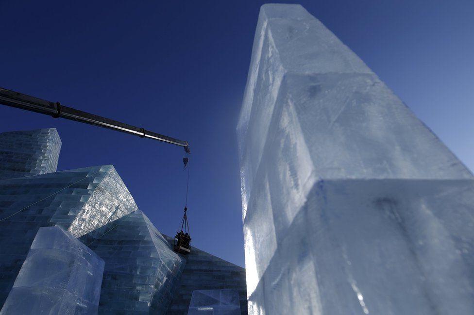 Workers polish an ice sculpture