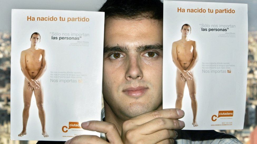 Albert River holds up two campaign posters showing himself naked, in Barcelona, Spain, 2006