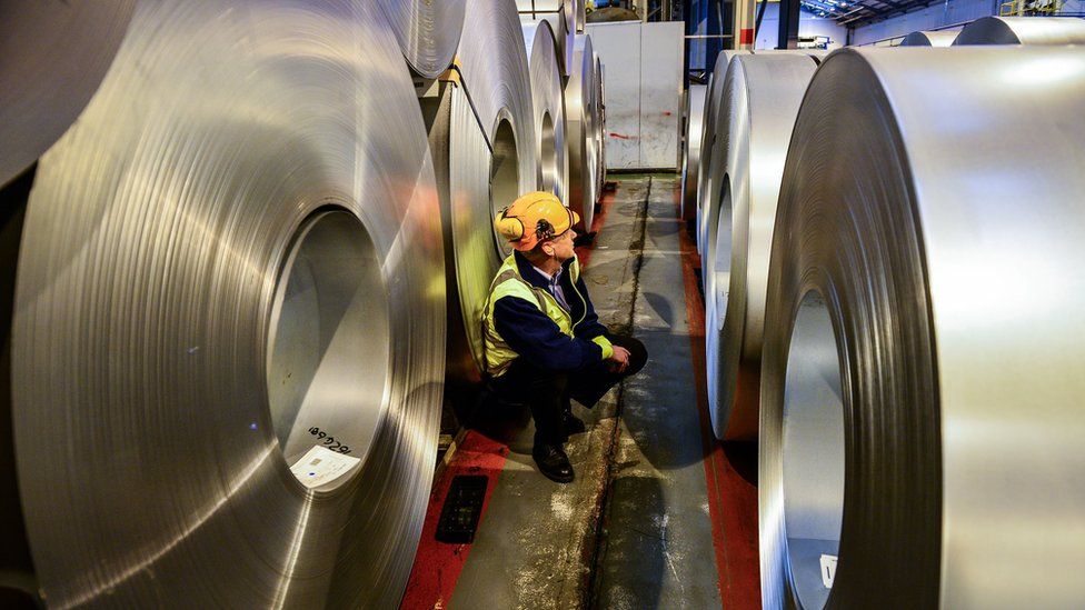 A worker inspects rolls of steel