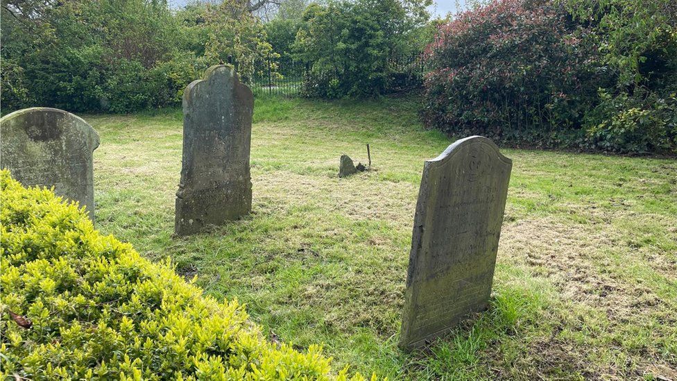 Grass graveyard with four old gravestones