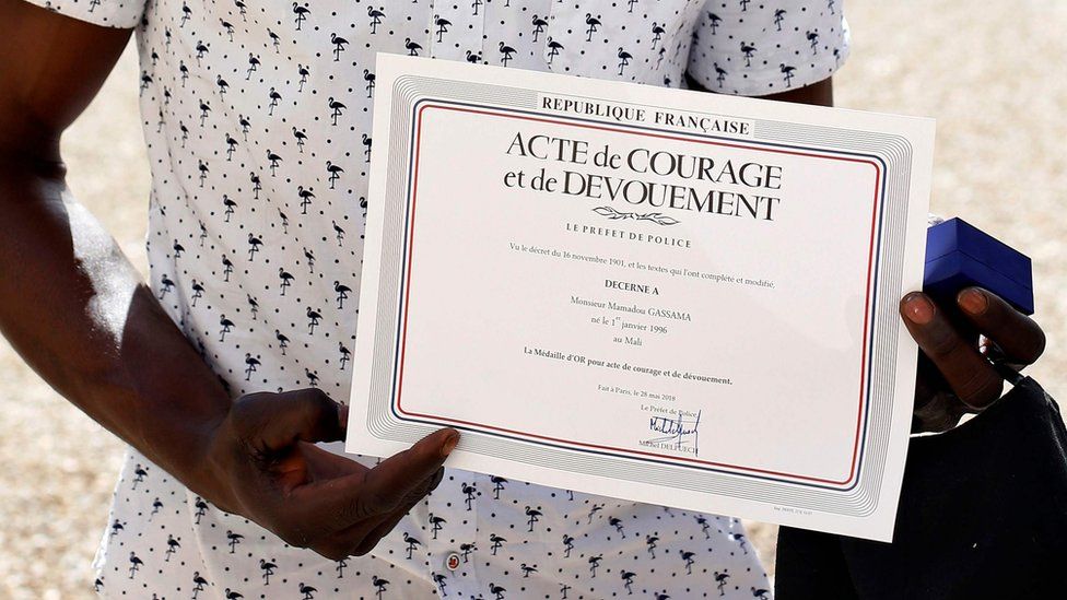Mamoudou Gassama holds a certificate he was given for climbing up a building to rescue a boy