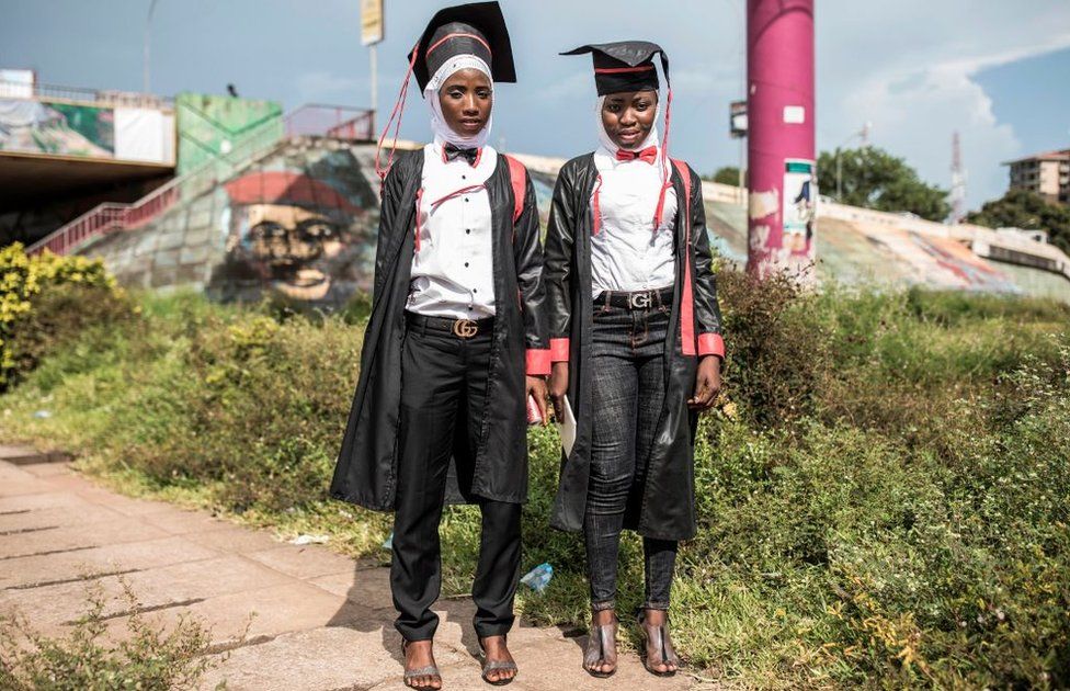 Two young women pose for a portrait, dressed in robes after collecting their Bachelor degrees in Conakry on October 12, 2020.