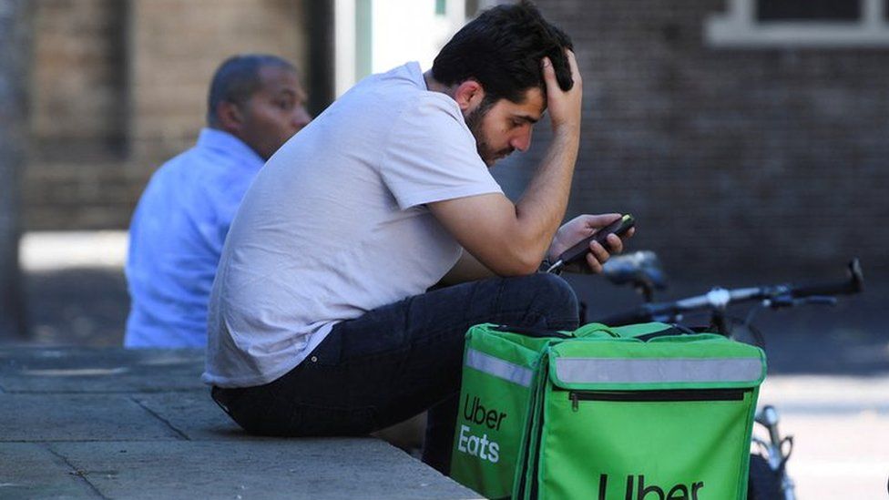 A bicycle courier from Uber Eats checks his phone in Utrecht , Netherlands.