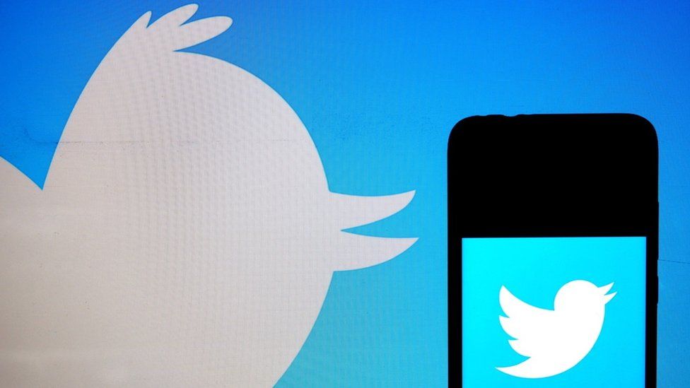 Twitter logo on phone on background of Twitter logo